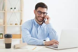Businessman talking on phone during his working day, solving business tasks, filling forms on laptop