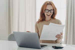 Happy excited redhead woman reading paper letter with notification about last mortgage payment