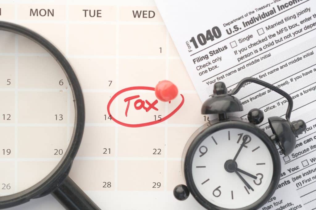 tax day concept with red circle on calendar date and tax return on table